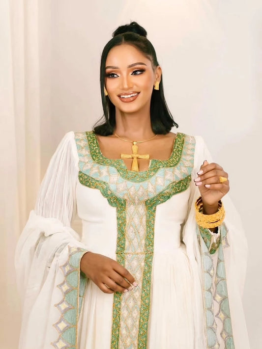 Woman wearing a traditional Habesha Kemiswith green and white patterns on a plain background