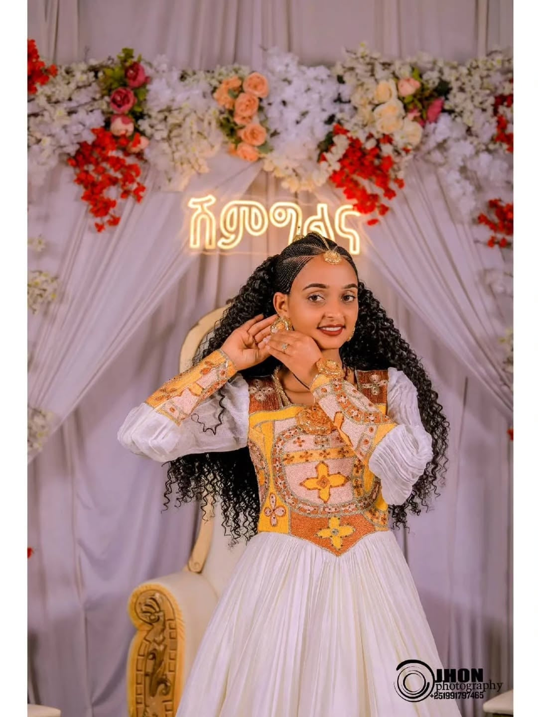 Woman in traditional Gold Ethiopian Wedding Dress with floral decorations and a neon sign in the background