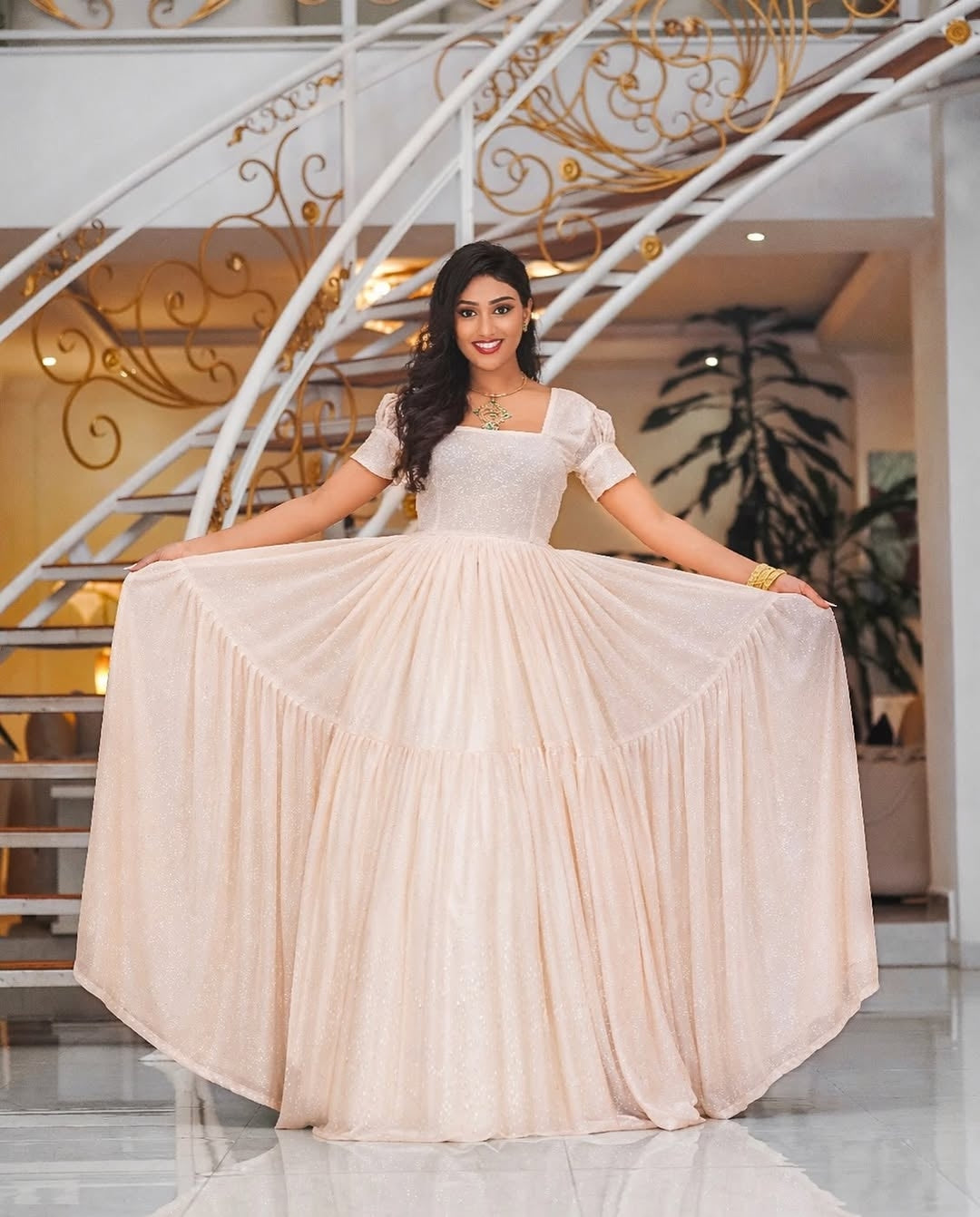 Woman in a white Habesha Chiffon Dress standing in a decorative interior setting