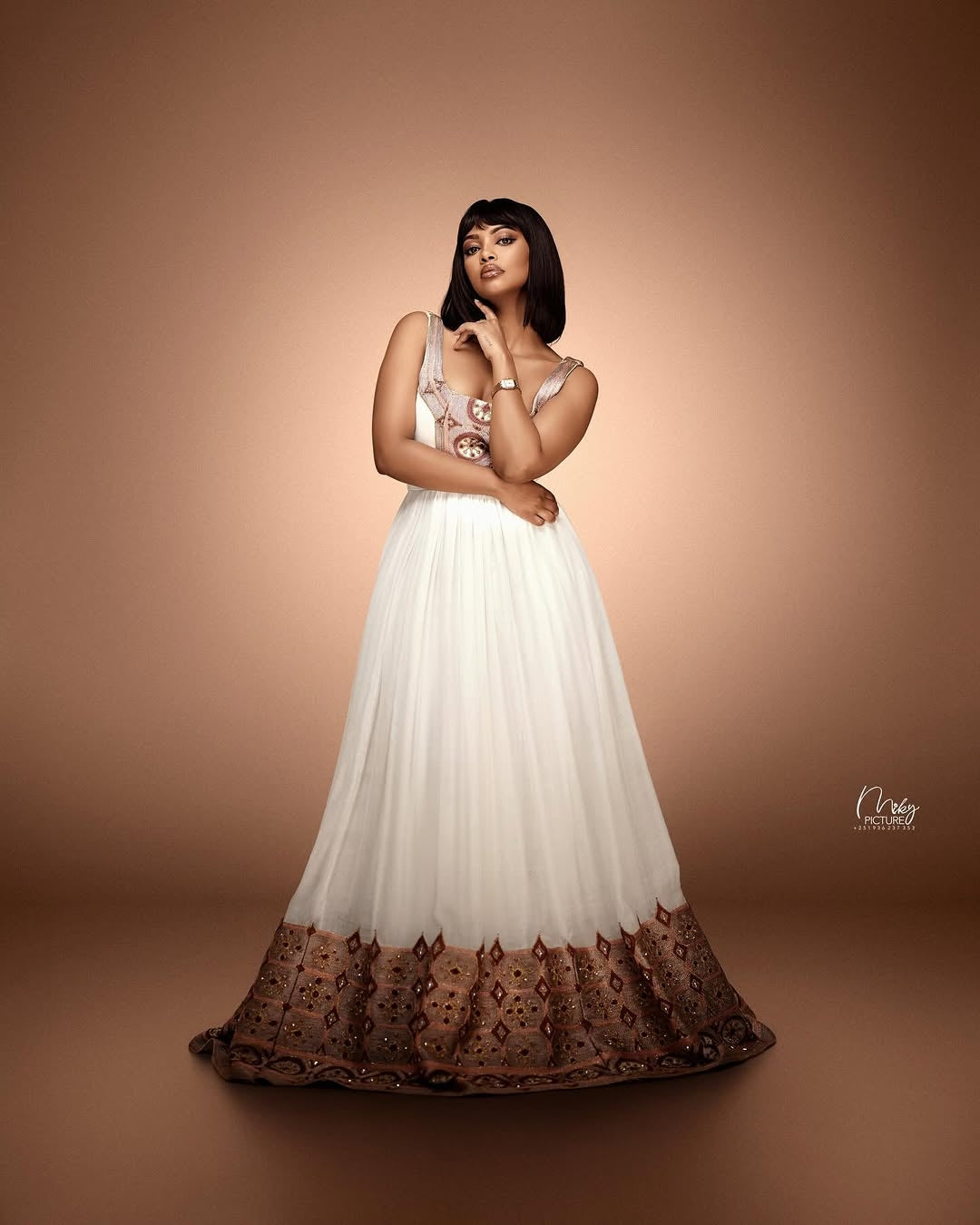 Woman in a white dress with brown lace details on a brown background