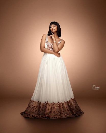 Woman in a white dress with brown lace details on a brown background