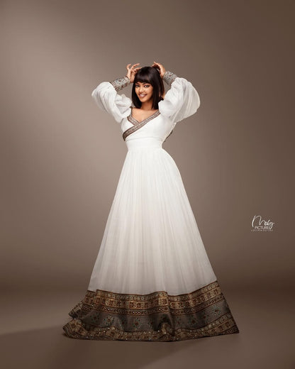 Woman wearing a white dress with patterned hem against a brown background