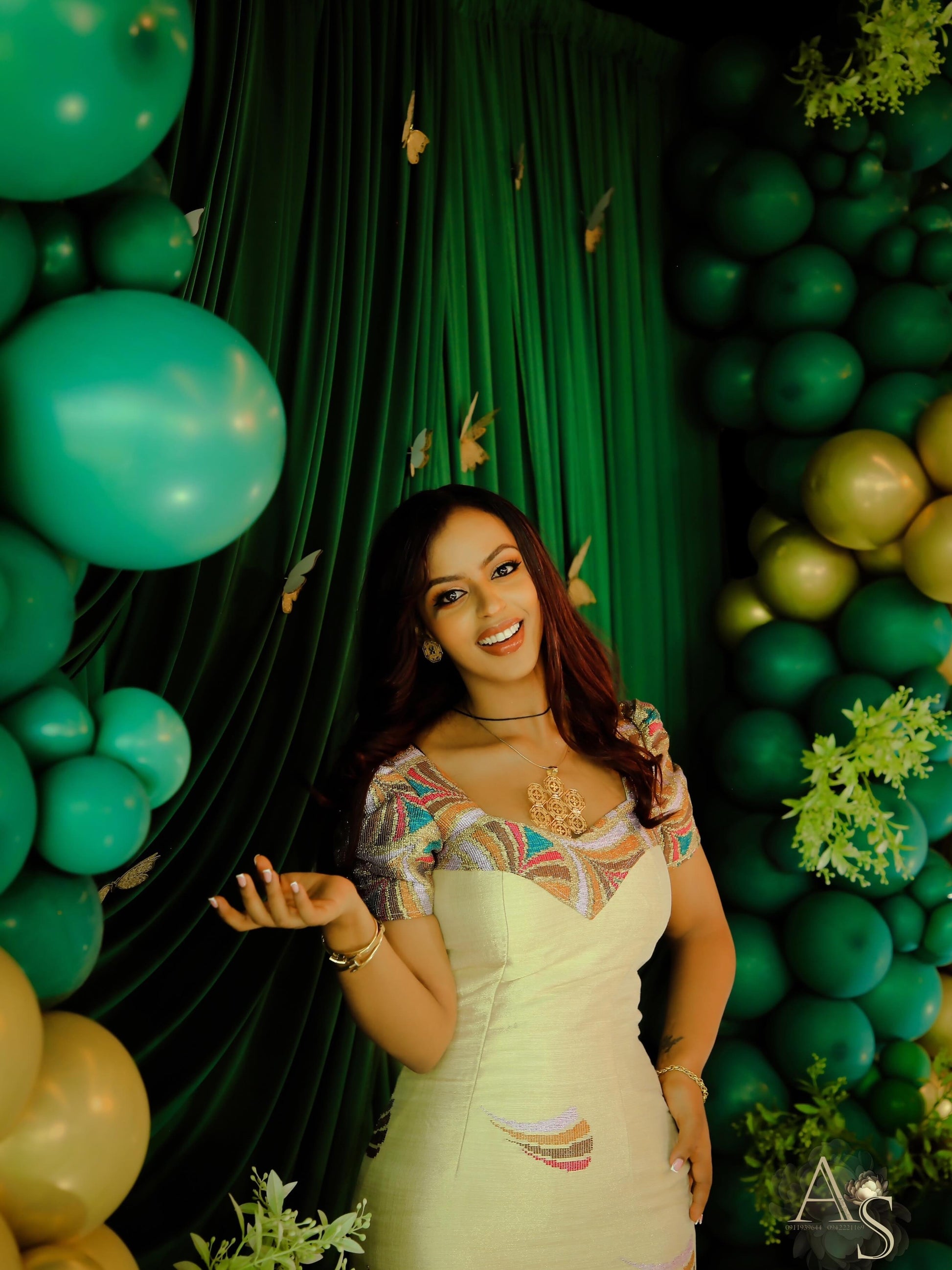 Woman posing in front of a green and gold habesha dress decoration