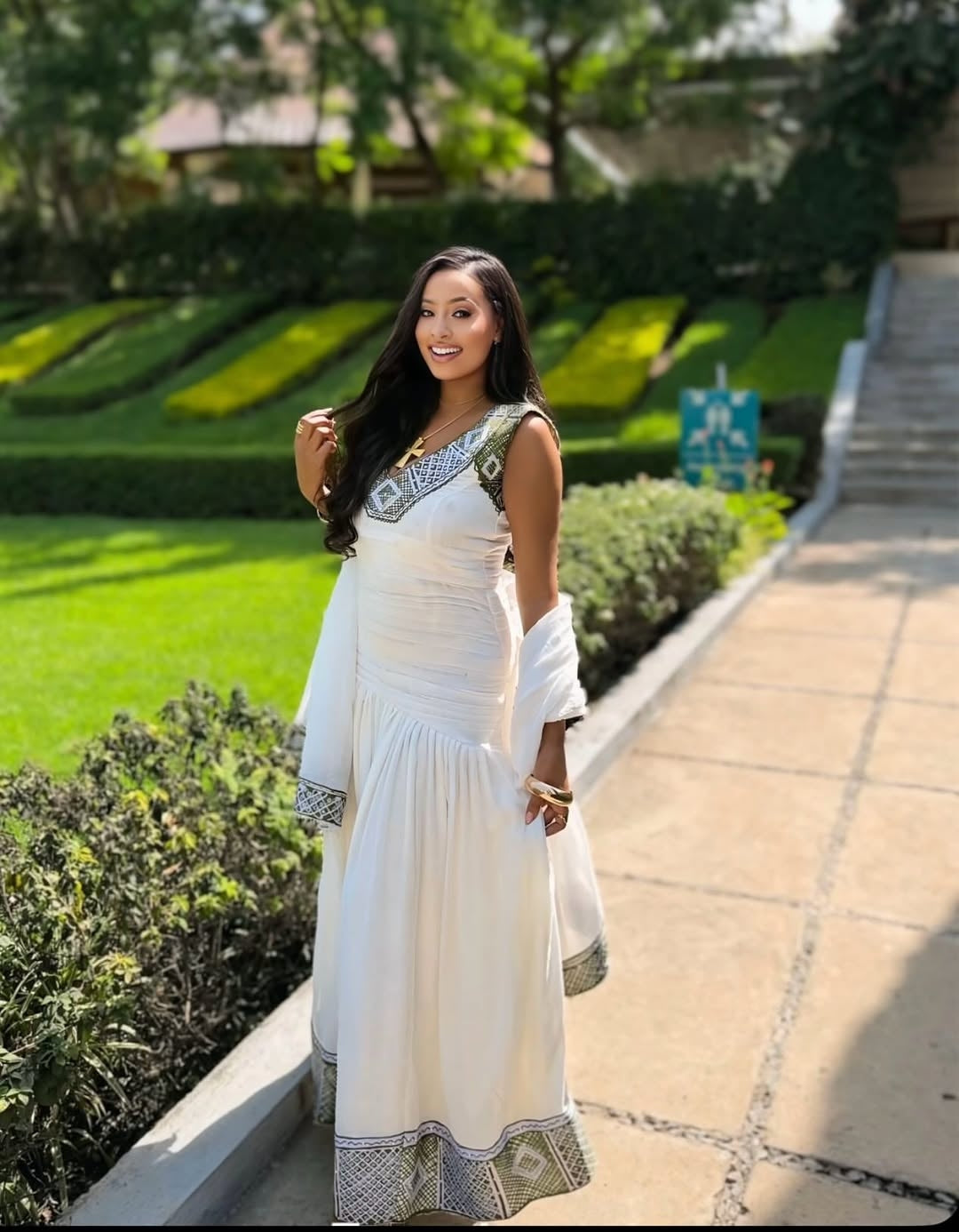 Woman in a white dress with greenery and a pathway in the background