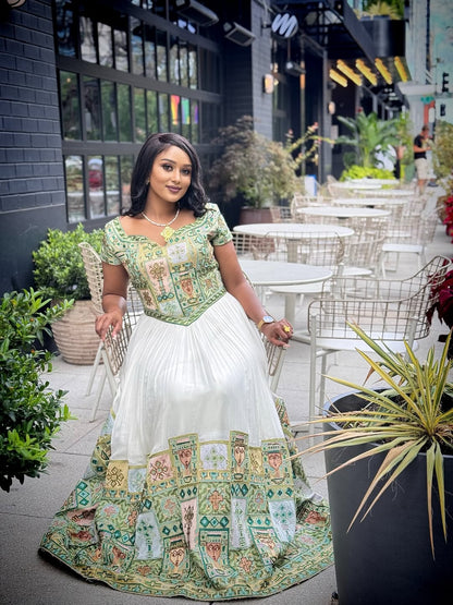 Woman in a traditional habesha kemis standing outdoors with tables and chairs in the background