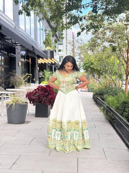 Woman in a floral habesha kemis standing on a sidewalk with greenery and a building in the background