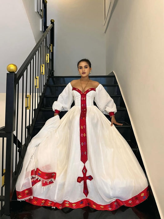 Woman in a white and red habesha dress sitting on a staircase