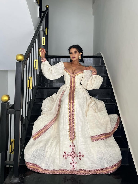 Woman in a white embroidered Ethiopian cultural dress standing on a staircase