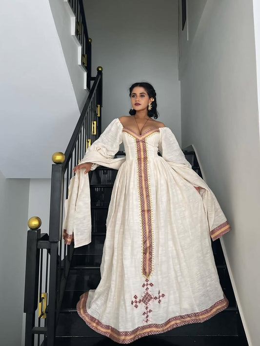 Woman in a white embroidered Ethiopian cultural dress standing on a staircase