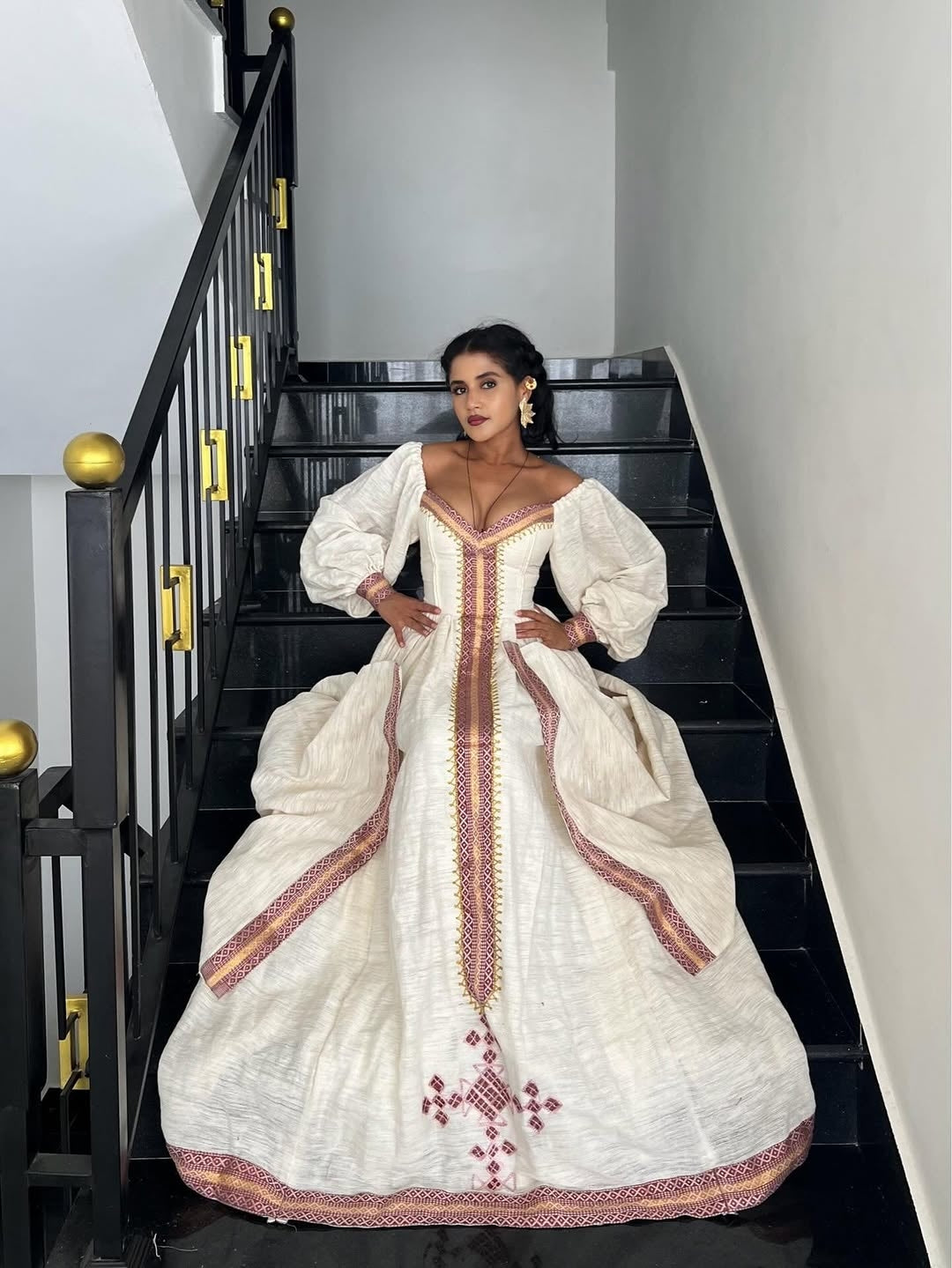 Woman in a white embroidered Ethiopian cultural dress standing on a staircase