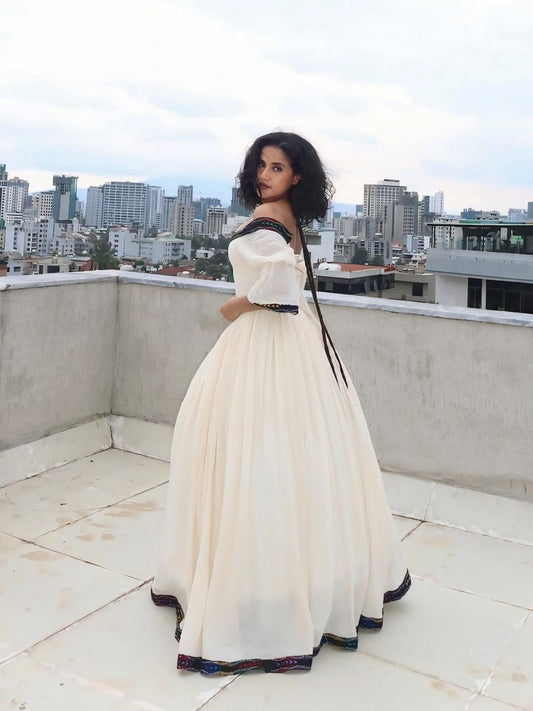Woman in a white dress with black accents on a rooftop with cityscape in the background