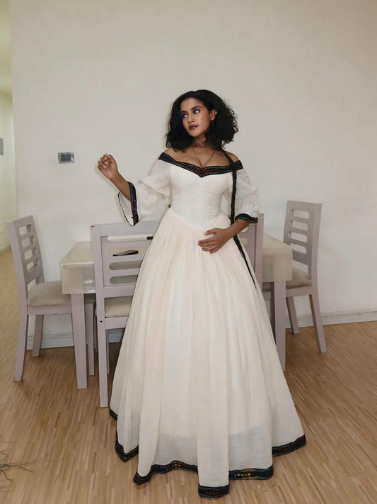 Woman in a white and black dress standing in a dining room.