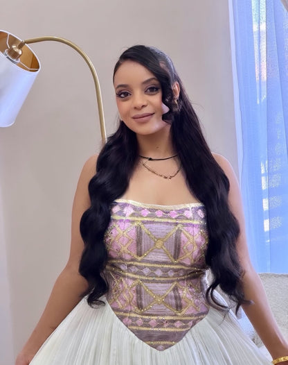 Woman wearing a patterned top and white Ethiopian dress indoors