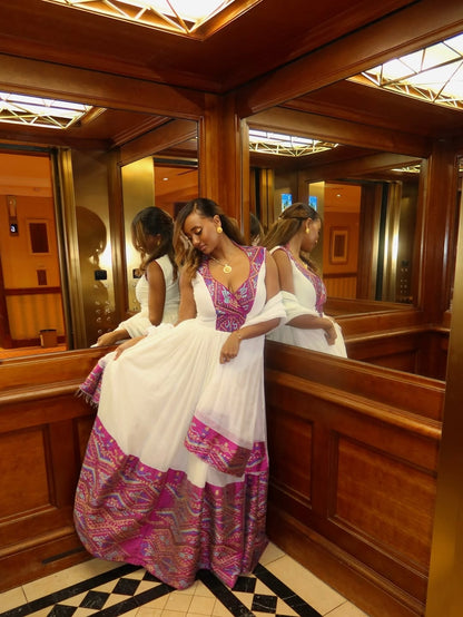 Woman in a colorful habesha dress standing in front of a mirror in an elevator.