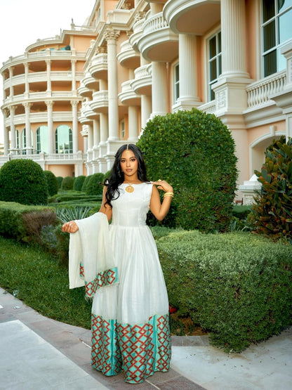 Woman in a white and patterned Ethiopian cultural dress  standing in front of a luxurious building.