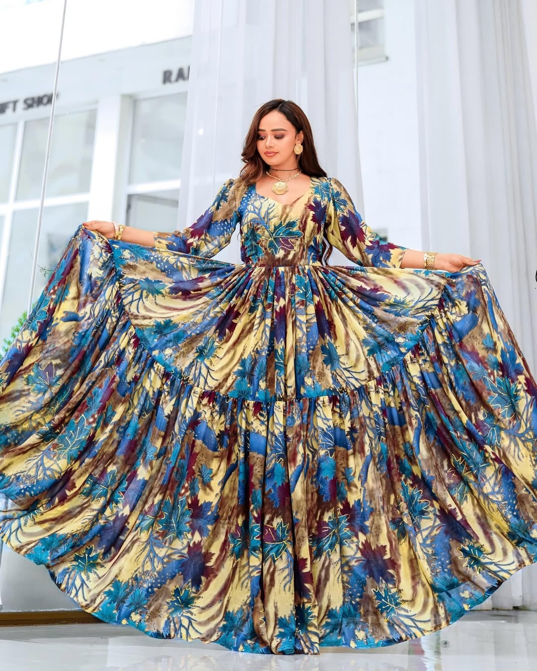 Woman wearing a colorful floral dress in a bright room.