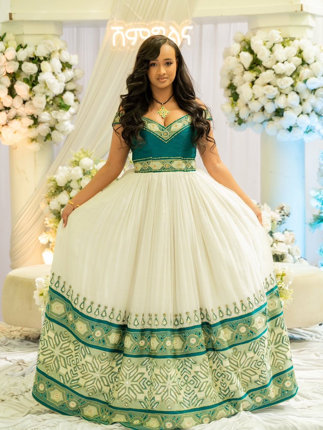 Woman in a green and white traditional Green Habesha Wedding Kemis – with floral decorations in the background
