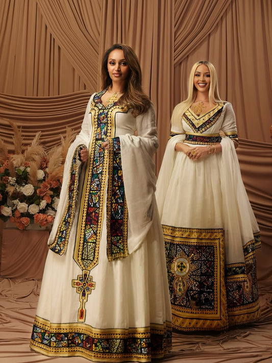 Two women in ornate, traditional habesha kemis standing against a decorative backdrop.