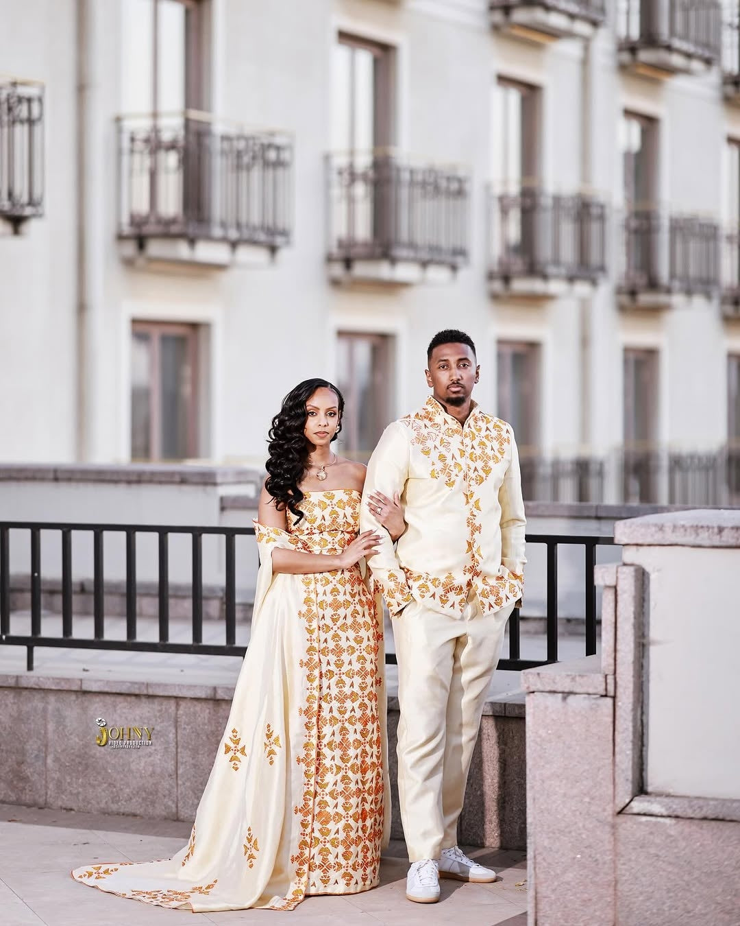 Couple in formal Red Ethiopian Traditional Dress standing on a rooftop with a building in the background