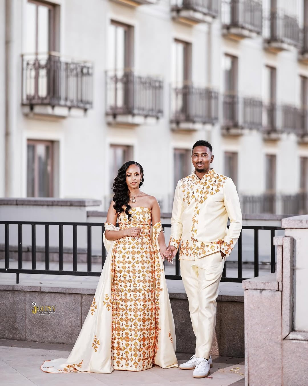 Couple in formal Red Ethiopian Traditional Dress standing on a rooftop with a building in the background