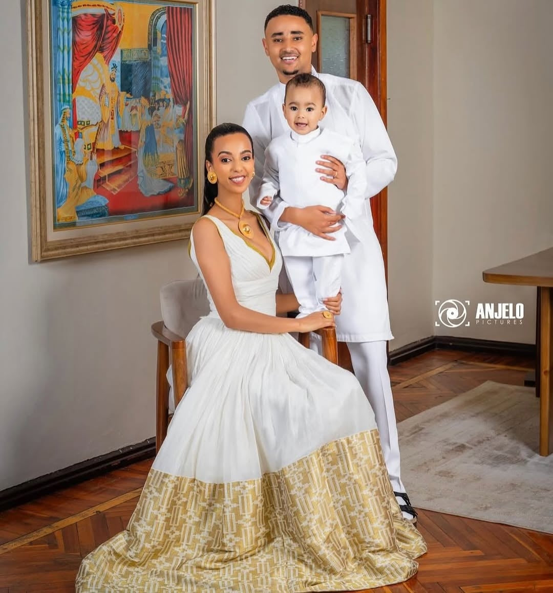 Family of three in formal habesha dress  posing indoors with a painting in the background