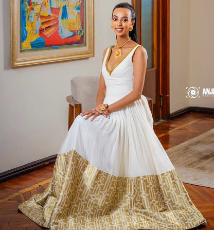 Woman in a white and gold dress sitting in a room with a painting on the wall.