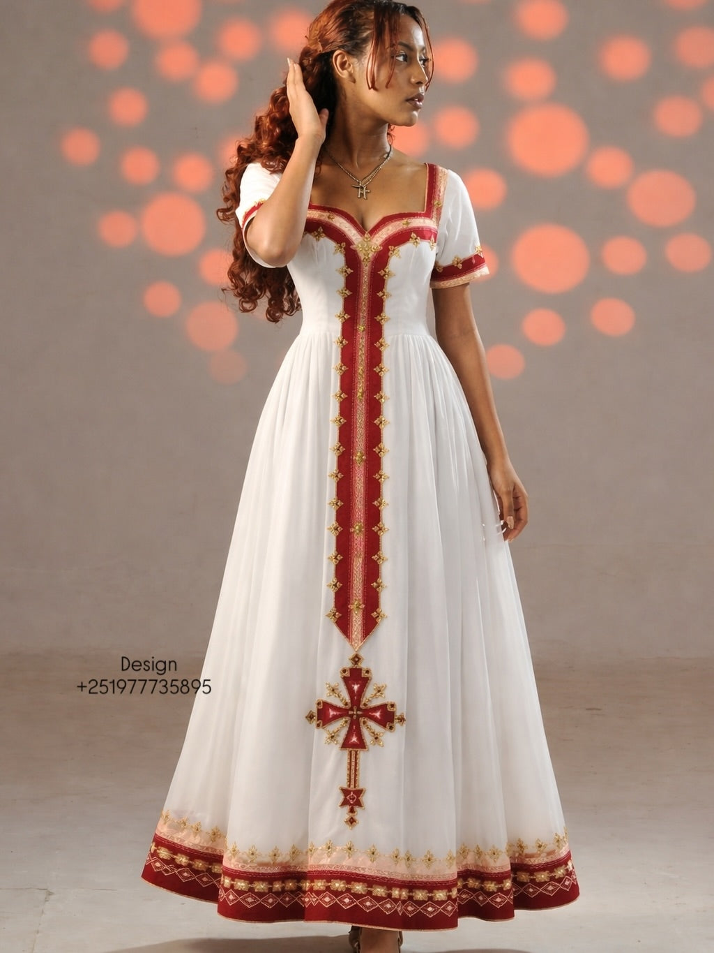 Woman wearing a white dress with red and gold embroidery against a neutral background