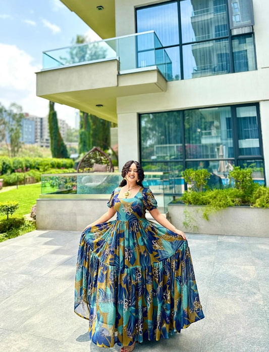 Woman in a blue floral habesha chiffion standing in front of a modern building with greenery.