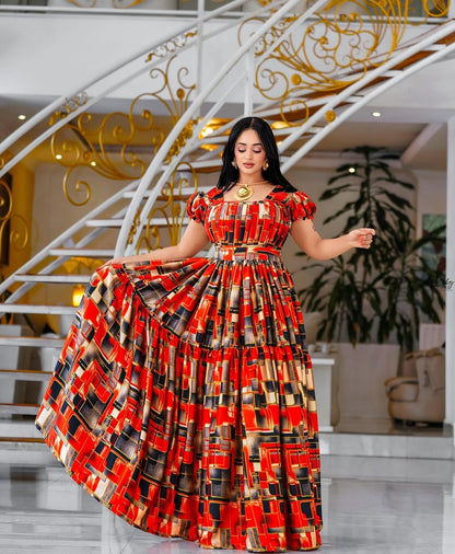 Woman in a red and black patterned Habesha Chiffon standing in an elegant interior setting.