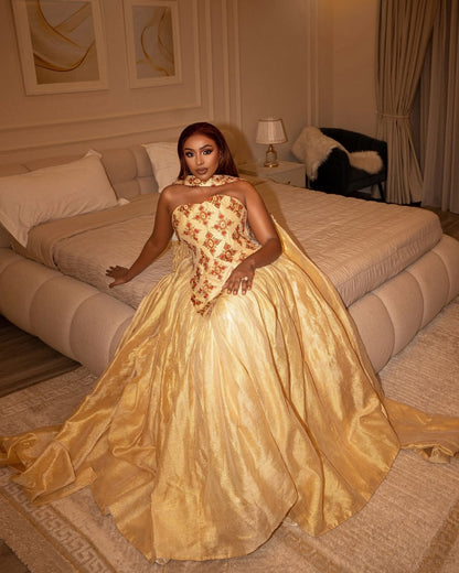 Woman in a gold and floral wedding  dress standing in a bedroom.